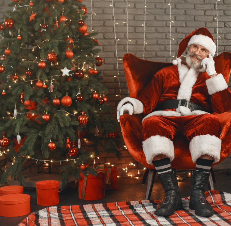 Santa sitting in a chair next to a Christmas tree